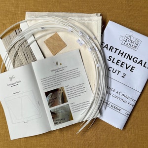 May include: A white fabric kit for making a Farthingale Sleeve Cut 2. The kit includes instructions, fabric, and plastic boning. The instructions include a diagram of the sleeve and steps for cutting and sewing.