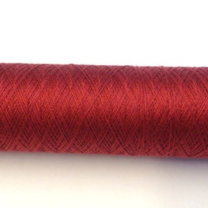 May include: A spool of red embroidery thread with the label "0/81S" on one end and "silk" on the other.