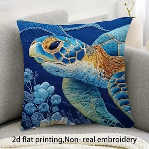 May include: A square cushion featuring an embroidered sea turtle design in shades of blue, gold, and green. The turtle is set against a dark blue backdrop with embroidered flowers. The text "2d flat printing, Non- real embroidery" is at the bottom of the cushion.