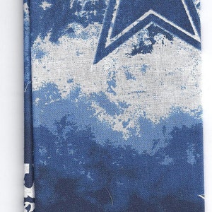 May include: A blue fabric with a white star and the word "BOYS" repeated. The design has a distressed, cloudy effect. The star is a prominent feature, with a five-pointed shape.