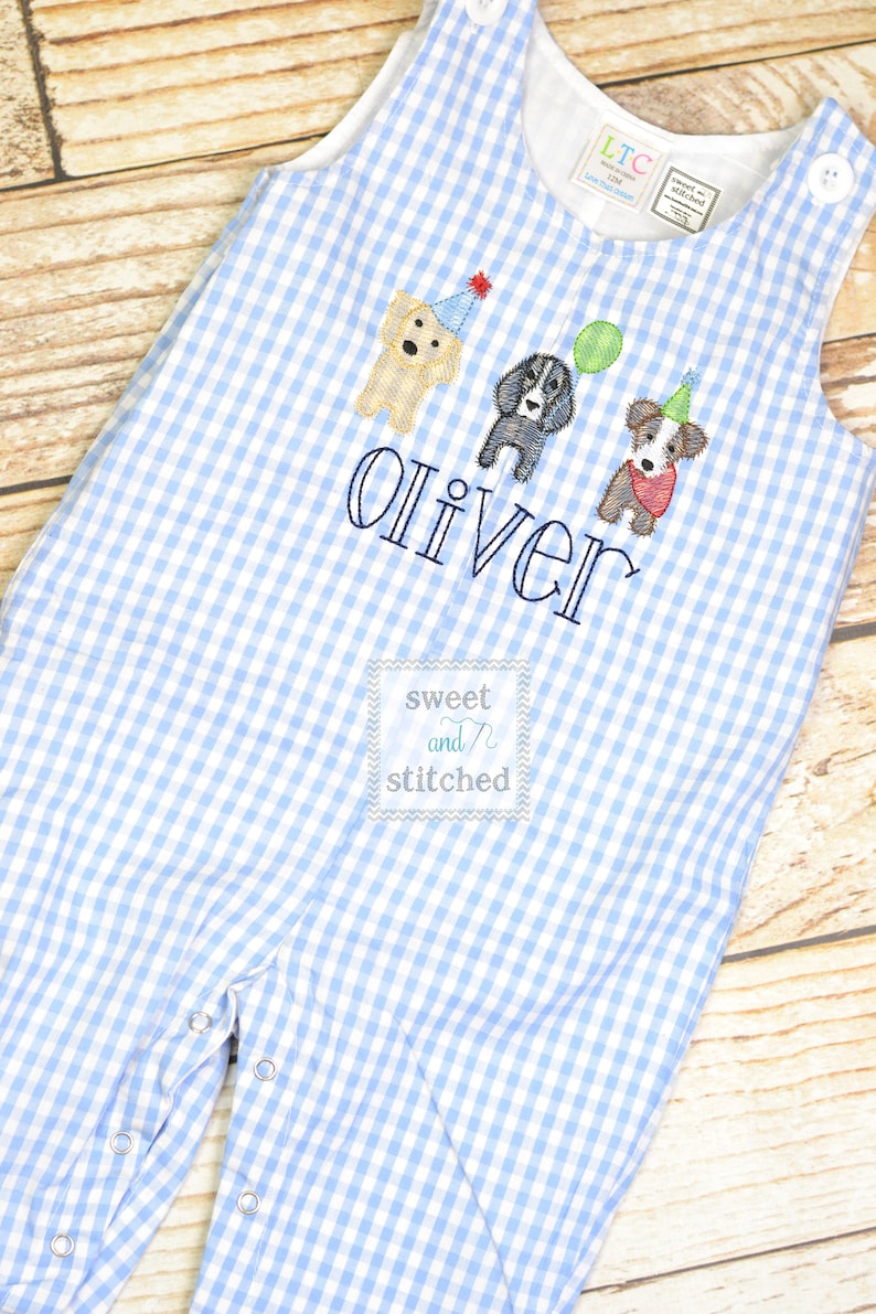 May include: Blue and white gingham baby overalls with embroidered dogs and the name "Oliver" in black thread. The overalls have a small label that says "sweet and stitched".