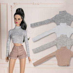 May include: Four long-sleeved turtleneck tops in grey, white, light grey, and beige. The tops are made of a soft, stretchy fabric and have a ribbed texture.