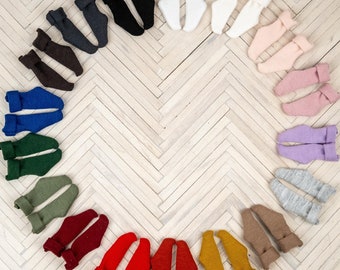 May include: A variety of colorful socks arranged in a circle on a white wood floor. The socks are made of different materials and have different patterns.