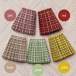 May include: Six pleated skirts in different colors and plaid patterns. The skirts are pink, red, beige, green, and yellow.