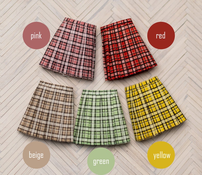 May include: Six pleated skirts in different colors and plaid patterns. The skirts are pink, red, beige, green, and yellow.
