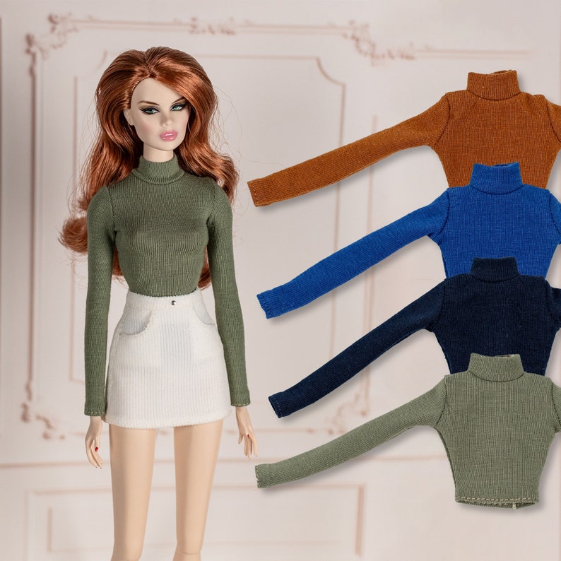 May include: Five doll-sized turtleneck sweaters in different colors: brown, blue, navy blue, and green. The sweaters are made of a ribbed fabric and have long sleeves.