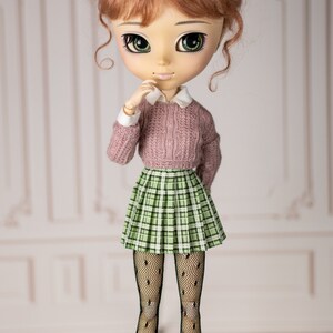 May include: A doll with red hair, green eyes, and a pink sweater, plaid skirt, and black tights.