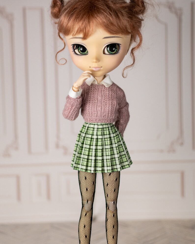 May include: A doll with red hair, green eyes, and a pink sweater, plaid skirt, and black tights.