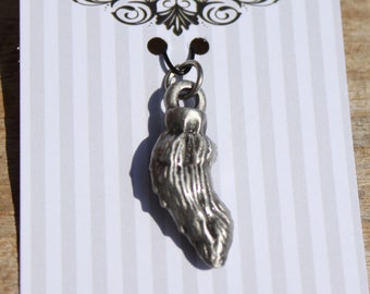 May include: A silver pewter charm shaped like a foot, hanging from a black cord. The charm is on a white card with the words "Fine Pewter" printed on it.