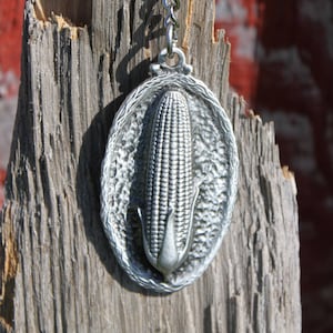 May include: A silver keychain featuring a detailed, three-dimensional corn cob design. The keychain is attached to a silver chain and ring.