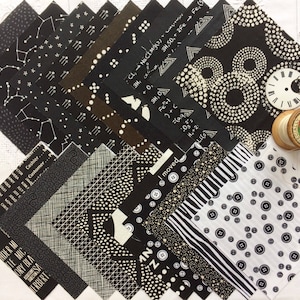 Peut inclure: Un ensemble de 16 carrés de tissu noir et blanc avec différents motifs, y compris des étoiles, des cercles, des rayures et des motifs géométriques. Les carrés de tissu sont disposés en éventail sur une surface blanche.