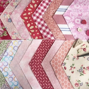 May include: A collection of pink and red fabric squares with various patterns, including floral, polka dots, gingham, and stripes. There are also buttons, thread, and scissors on the table.
