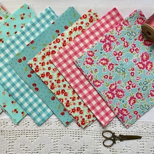 May include: A set of six fabric squares in a variety of patterns, including floral, gingham, and cherry prints. The squares are in shades of pink, blue, and white. There are also spools of thread, buttons, and a pair of scissors.
