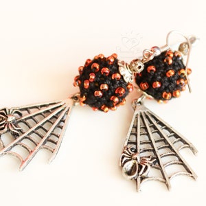 May include: A pair of black and orange beaded earrings with silver spider web and spider charms.