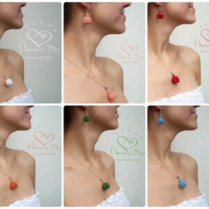 May include: Six women wearing white tops and silver necklaces with different colored beaded pendants and matching earrings. The pendants and earrings are all round and have a textured surface. The colors of the pendants and earrings are white, coral, red, green, orange, and blue.