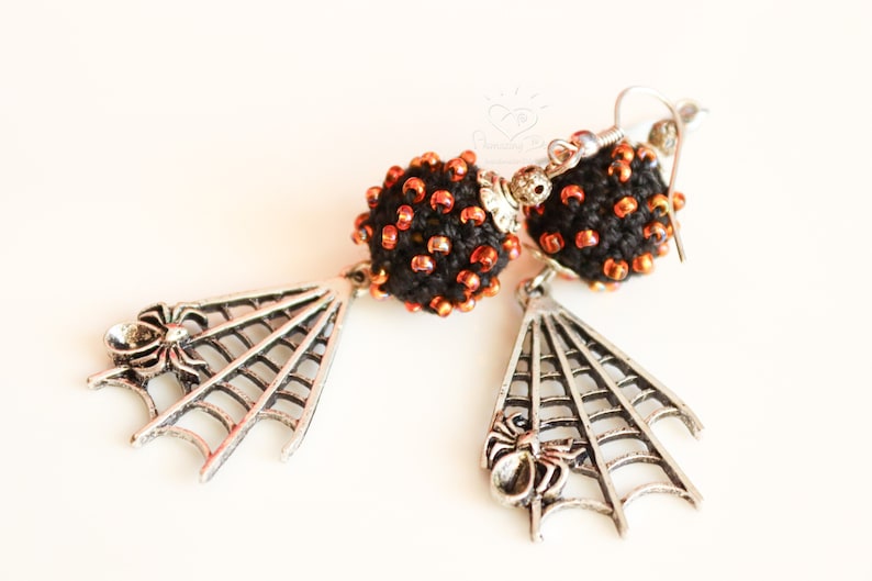 May include: A pair of black and orange beaded earrings with silver spider web and spider charms.