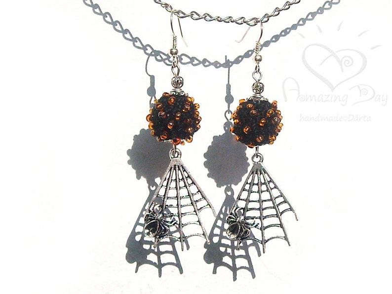 May include: Black and orange beaded dangle earrings with a silver spider web and spider charm.