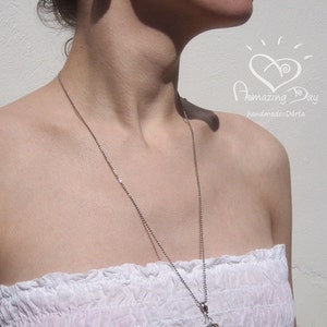 May include: A woman wearing a white strapless top with a silver chain necklace and a crocheted pendant. She is also wearing a pair of crocheted earrings. The necklace and earrings are both beige in color.