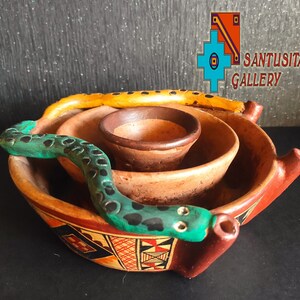 May include: A set of three terracotta bowls with a green and black snake design. The bowls are nested inside each other and have a geometric pattern around the rim.