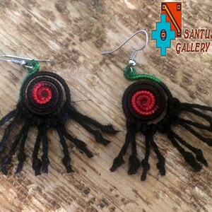 May include: Handmade black earrings with a spiral red centre and dangling strands. The earrings have a green accent and silver hooks. The image includes the text "SANTUSITAY GALLERY".