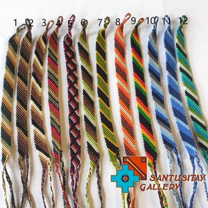 May include: Twelve colorful friendship bracelets with various striped patterns in black, white, brown, red, green, orange, blue, and yellow. The bracelets are tied together at the top and have long tassels.