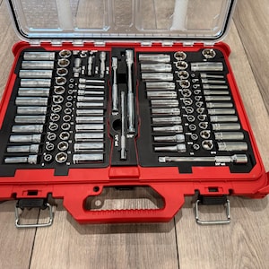 May include: A comprehensive mechanic tool set housed in a bright red plastic carrying case with a clear lid. The interior features a black foam organizer containing numerous chrome-finished metal sockets, various drive extensions, and ratchets.