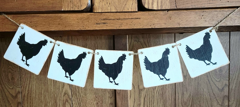 May include: A white wooden banner with black silhouette chickens. The banner is strung together with twine and has five sections.