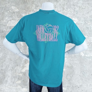 May include: Teal-colored t-shirt with a graphic on the back that reads "JAVA '92 VOLLEYBALL" in pink and green. The design includes a volleyball graphic. The shirt is displayed on a mannequin.