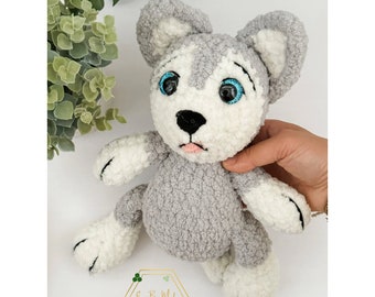 May include: A gray and white crocheted stuffed animal resembling a husky dog. The toy has blue eyes and a pink tongue sticking out.