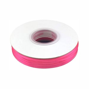 May include: A spool of bright pink ribbon, wound around a white cardboard core.