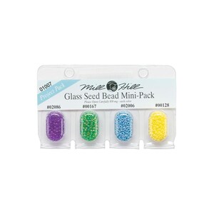 May include: A Mill Hill Glass Seed Bead Mini-Pack with four compartments. Each compartment holds a different color of glass seed beads: purple, green, blue, and yellow. The package includes the text "Project Pack".