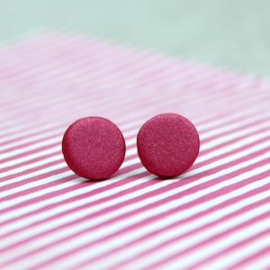 May include: Two pink oval-shaped earrings with a textured surface.