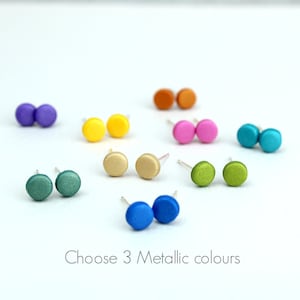 May include: Assortment of small, round, metallic stud earrings in various colours, including gold, blue, green, pink, yellow, and purple. Choose 3 metallic colours.