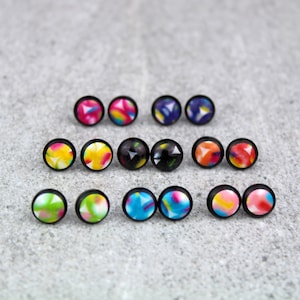 May include: A set of 12 colourful stud earrings with geometric patterns. The earrings are black with a variety of colours including yellow, blue, pink, red, and green.