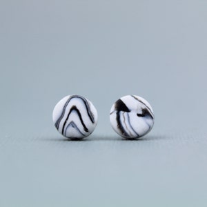 May include: A pair of black and white marble-patterned stud earrings.
