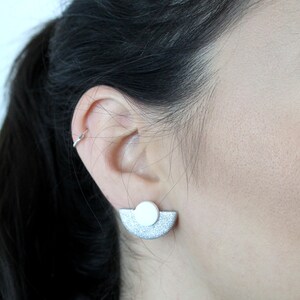 May include: Silver and white geometric earrings with a half-circle shape and a round accent.