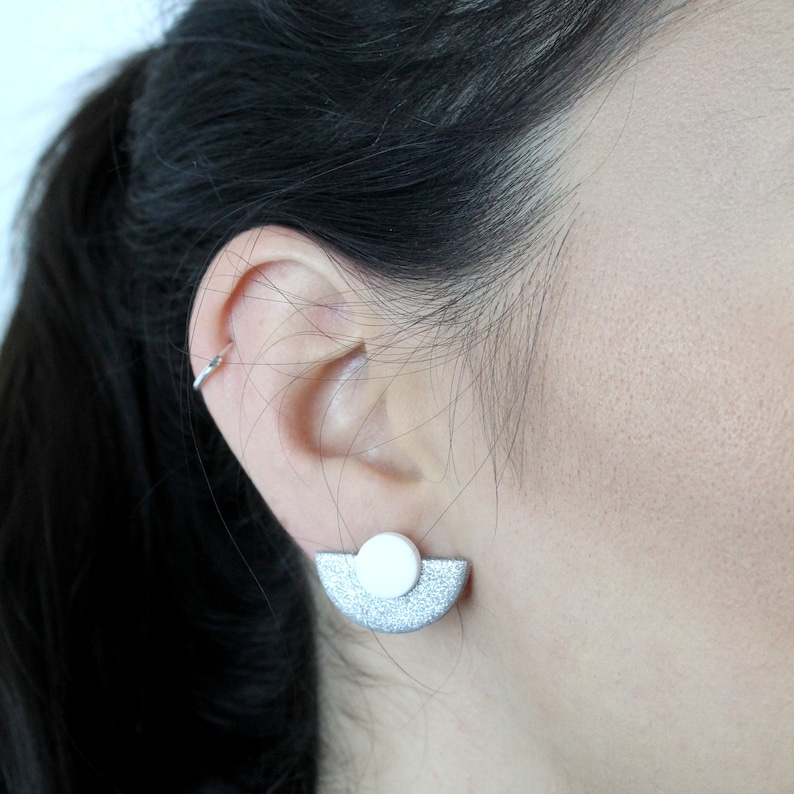 May include: Silver and white geometric earrings with a half-circle shape and a round accent.