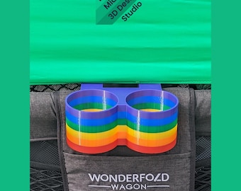 May include: A dual cup holder attachment for a Wonderfold Wagon, featuring a vibrant rainbow-striped design with horizontal bands of purple, blue, green, yellow, orange, and red. The text Layered Midwest 3D Design Studio is visible above.
