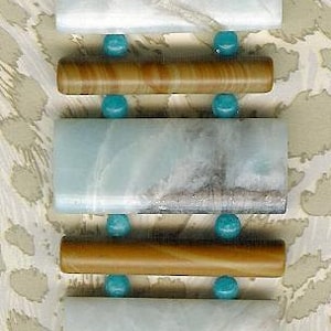 May include: A turquoise and brown bracelet with rectangular turquoise stones and brown wooden beads. The bracelet has silver clasps.