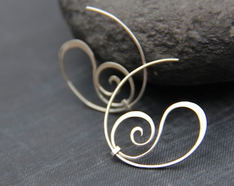 Puede incluir: Un par de pendientes de aro de plata con un diseño en espiral. Los pendientes están hechos de alambre fino y tienen un aspecto delicado y femenino.