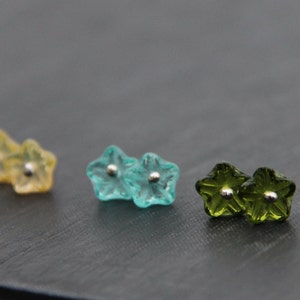 May include: Three pairs of flower-shaped earrings in yellow, blue, and green. Each earring has a small silver bead in the center.