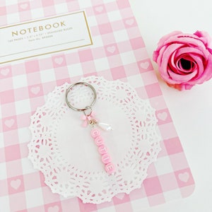 Llavero con lazo y cuentas con letras de Cutie rosa, dije para bolso