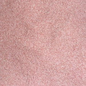 May include: A close-up of a pink textured surface. The surface is made of small, evenly distributed particles.
