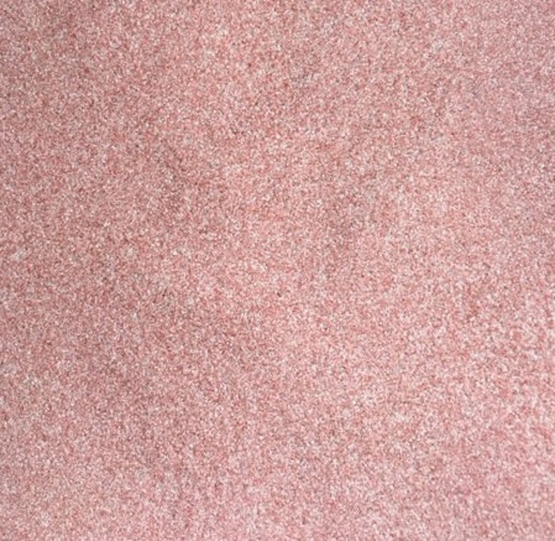 May include: Close-up of a textured surface with a speckled pattern. The color is a soft, muted pink, with variations in tone creating a subtle visual depth. The texture appears to be granular, with tiny particles.