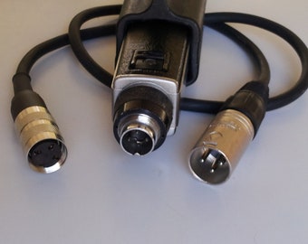 May include: A black and silver audio cable with multiple connectors. The cable has a black rubberized coating and silver-colored metal connectors. The connectors include a 4-pin XLR and a 3-pin XLR connector.