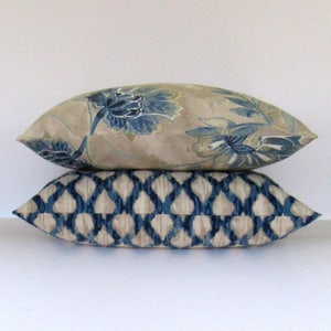 K&ouml;nnte beinhalten: Zwei dekorative Kissen, eines mit einem Blumenmuster in Blau- und Beiget&ouml;nen, das andere mit einem geometrischen Muster in Blau- und Beiget&ouml;nen.