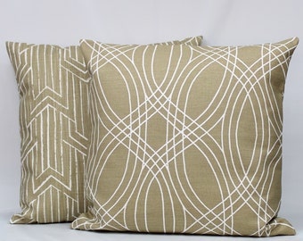 Op de afbeelding: Twee decoratieve kussens met geometrische patronen. Het kussen aan de linkerkant heeft een wit en beige geometrisch patroon. Het kussen aan de rechterkant heeft een wit en beige geometrisch patroon met gebogen lijnen.