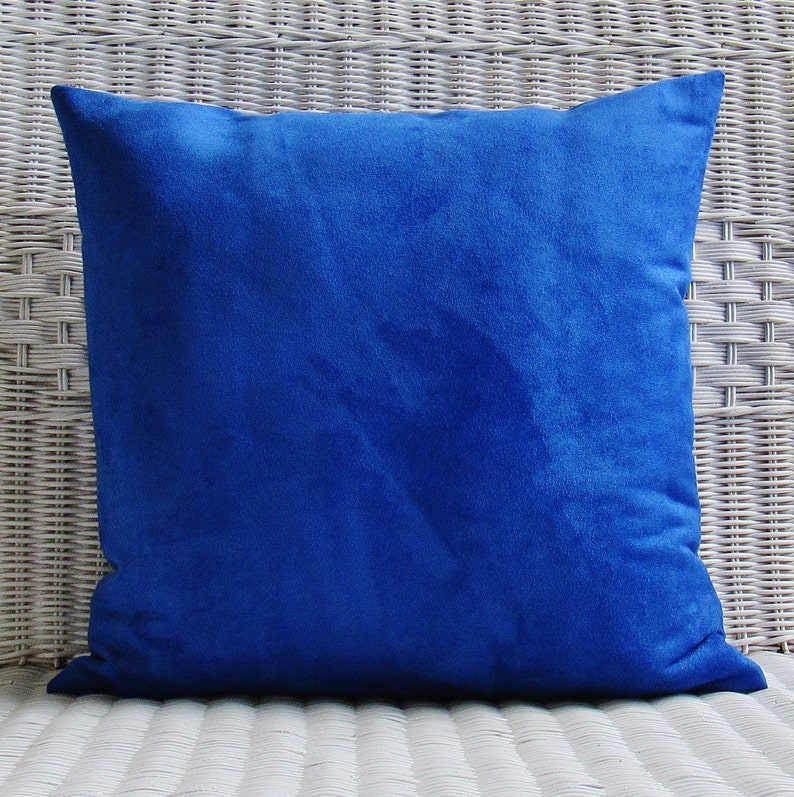 Op de afbeelding: Een helderblauw vierkant kussen met een zachte, fluweelzachte textuur.