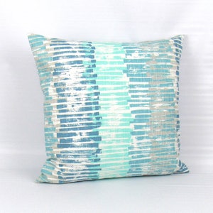 Puede incluir: Una almohada decorativa con un patr&oacute;n de rayas azules y blancas. Las rayas son de color azul claro, azul oscuro y gris claro. La almohada est&aacute; hecha de una tela suave y texturizada.