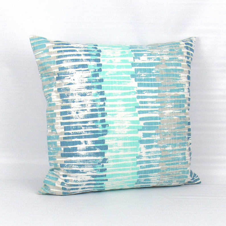 Puede incluir: Una almohada decorativa con un patr&oacute;n de rayas azules y blancas. Las rayas son de color azul claro, azul oscuro y gris claro. La almohada est&aacute; hecha de una tela suave y texturizada.